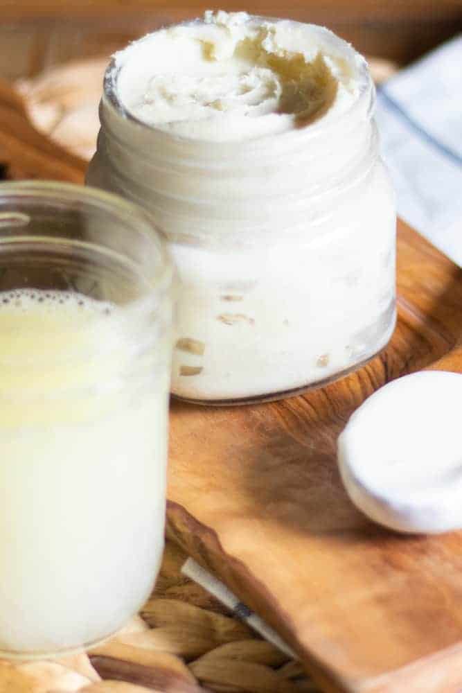 Mason jar of homemade face moisturizer on wooden cutting board. 