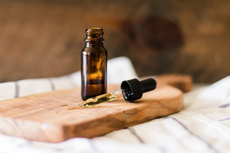 Amber colored bottle of vitamin E oil with dropper top laying next to it.