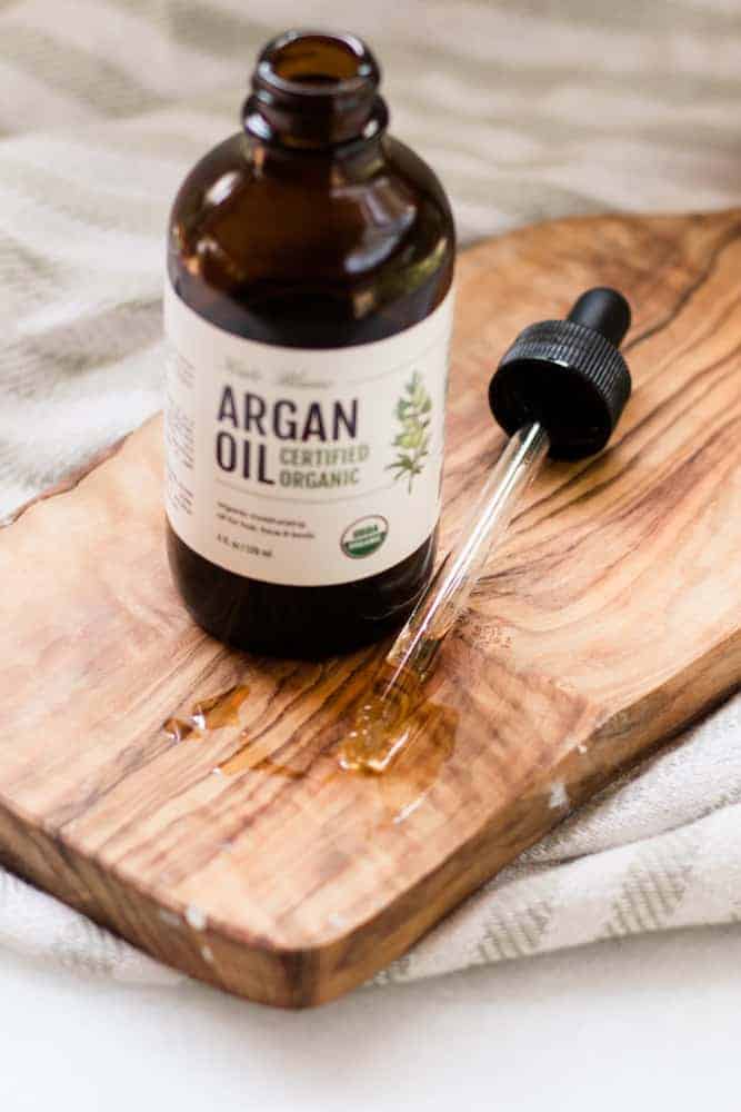 Bottle of open argan oil on wood board. 