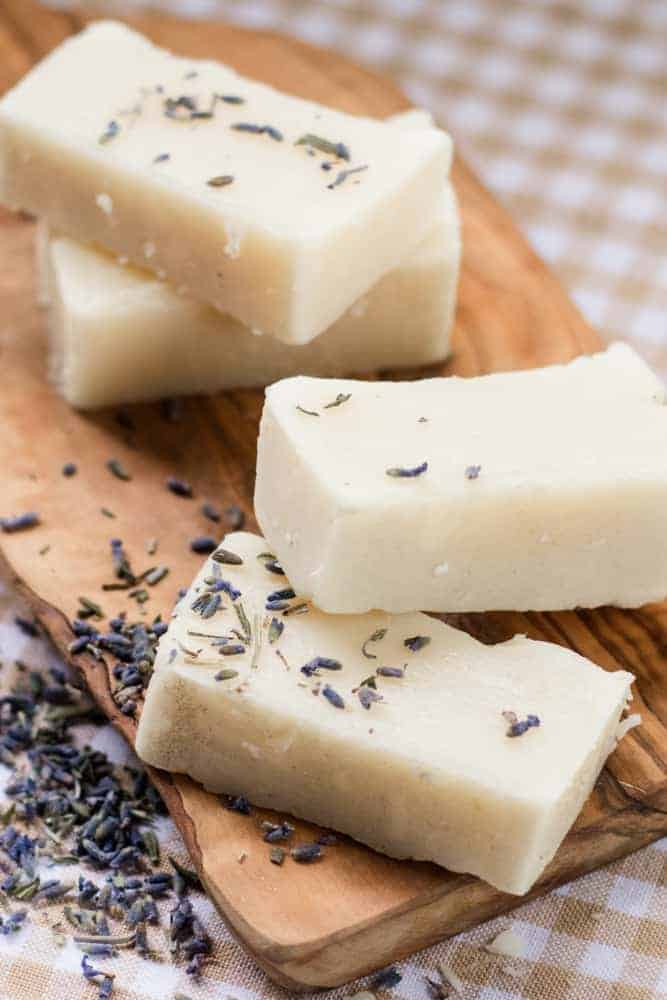 DIY baby soap bars on wooden board with lavender buds sprinkled around.