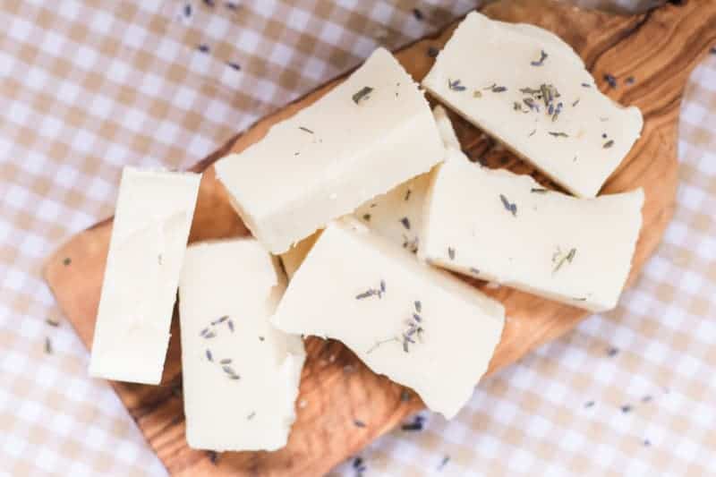 Cold-process soap bars on wooden board with lavender buds.