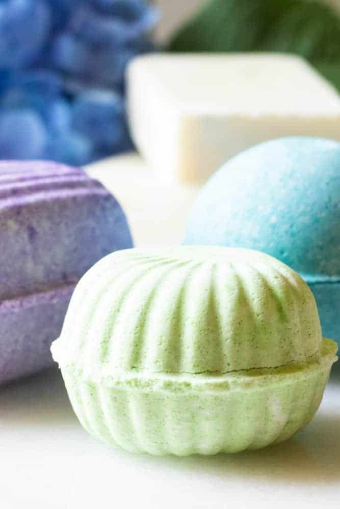 TropIcal bath bombs on white marble table with bright flowers behind them.