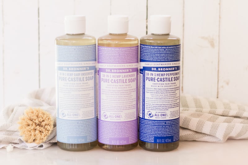 Bottles of castile soap, one light blue, one purple, and one dark blue. 