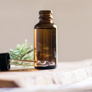 A homemade beard growth oil in an amber colored dropper bottle with the dropper top laying next to it.