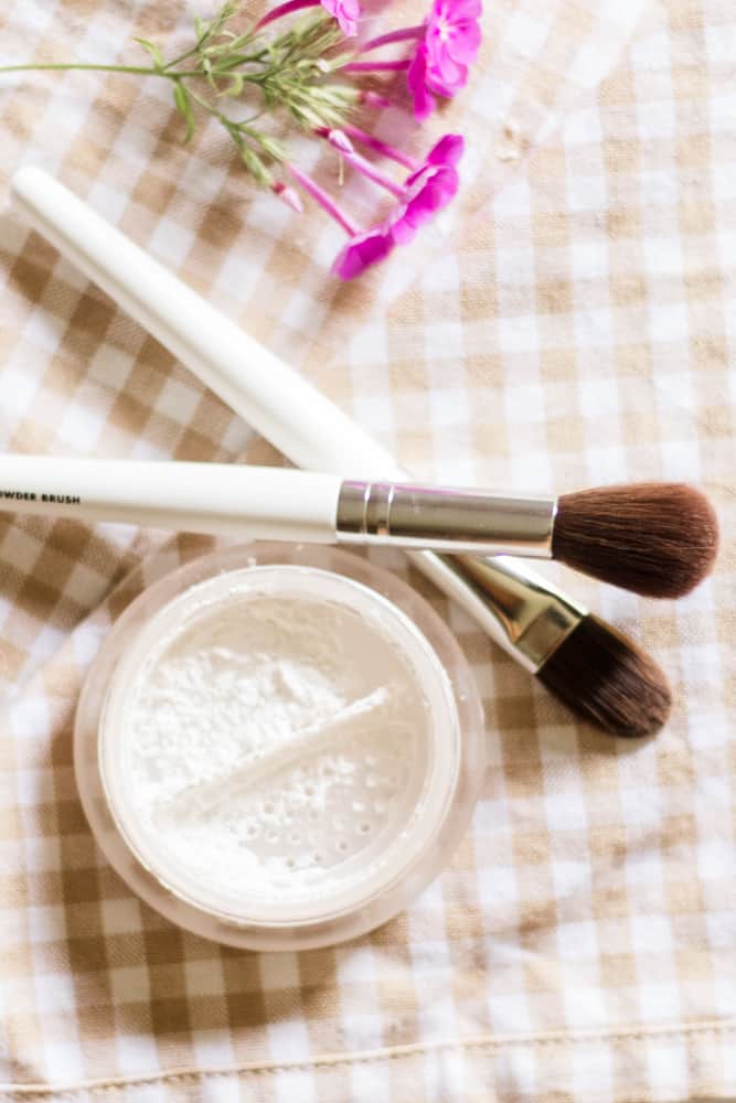 Homemade white setting powder in glass airtight container with 2 makeup brushes.