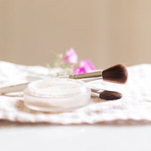 Homemade setting powder in a shallow dish with an applicator brush next to it.
