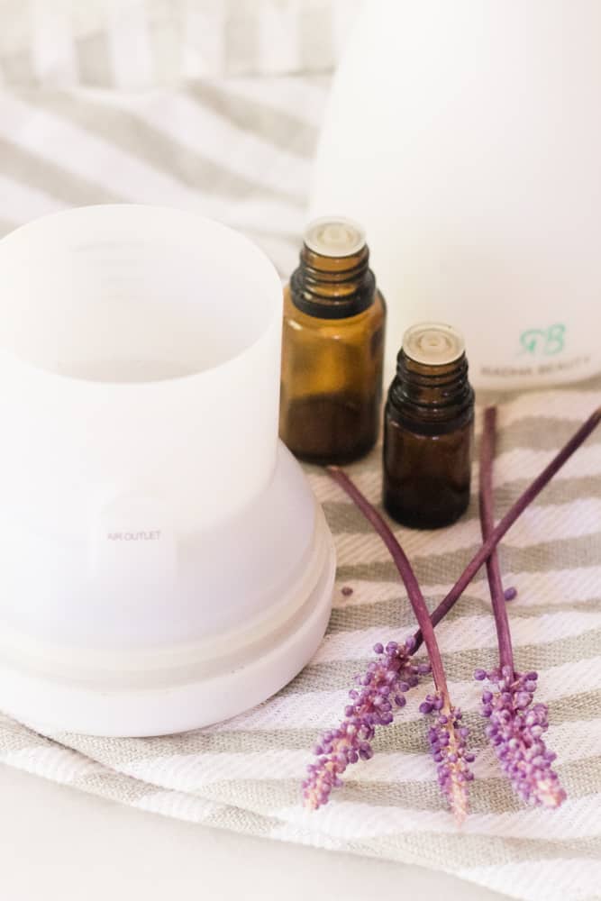 Essential oil diffuser and lavender on white and gray towel.