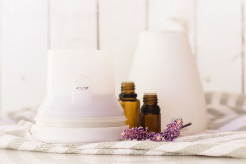 White diffuser on white marble table and lavender sprigs by it.