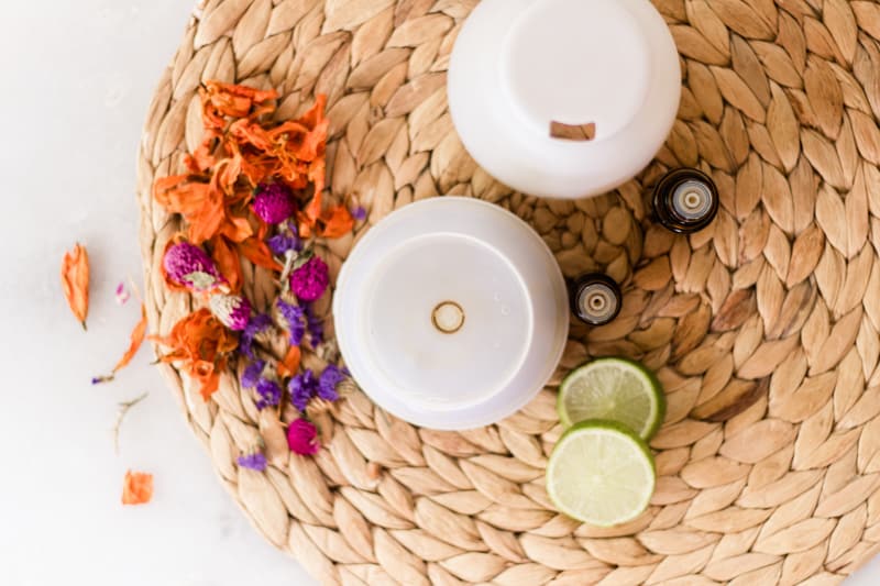 Diffuser with bright flowers and lime slices around it. 