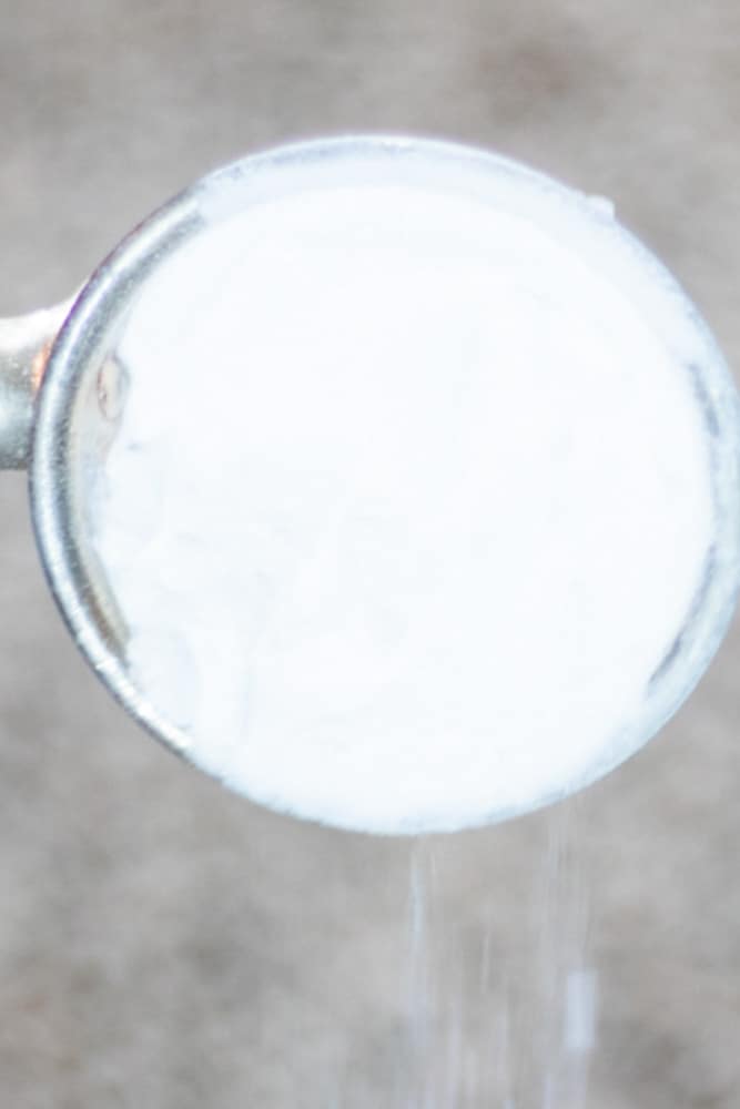 Pouring Baking soda onto carpet stain.