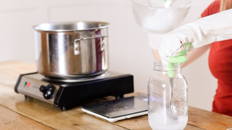 Mixing water and lye into glass mason jar.