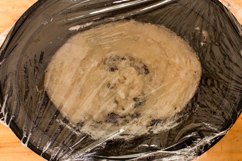 Oils for soap in a crockpot covered with plastic wrap. 