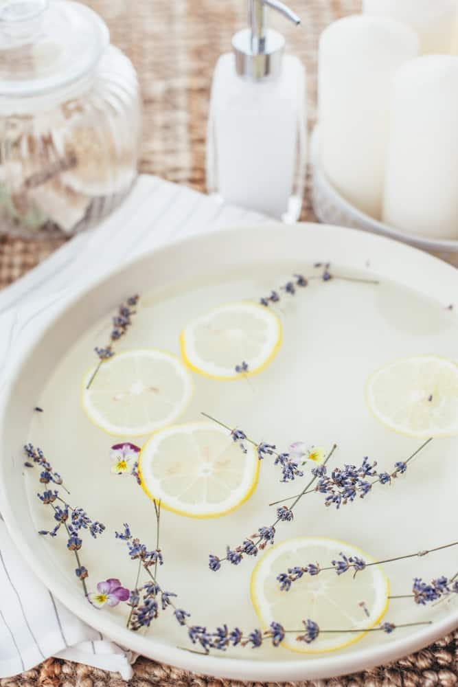 White bowl of at home foot soak with lemon slices and dried lavender. 