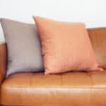 A leather sofa with throw pillows on it.