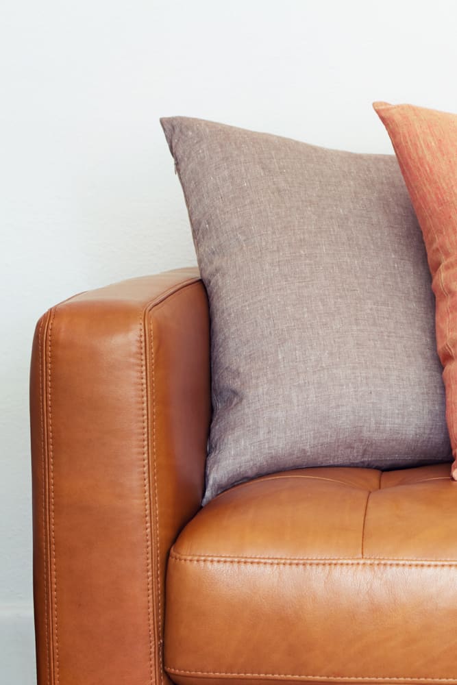 Up close picture of leather couch with throw pillows on it.