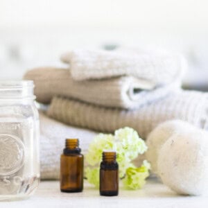 Homemade fabric softener on a laundry folding table with towels and dryer balls next to it.