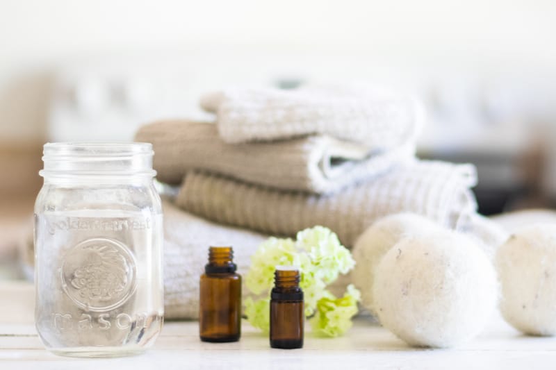 Homemade fabric softener on a laundry folding table with towels and dryer balls next to it.