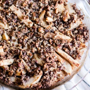 Paleo apple pie in a glass pie dish on a blue and white striped towel.