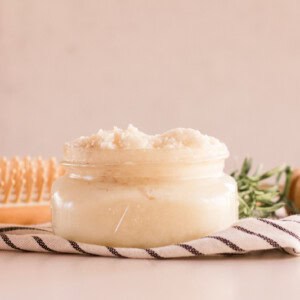 A diy protein hair treatment cream in a shallow glass container. Surrounded by a comb, towel and a honey comb.