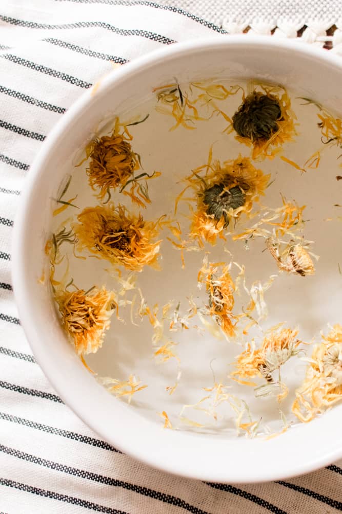 White glass face steaming bowl with dried yellow flowers.