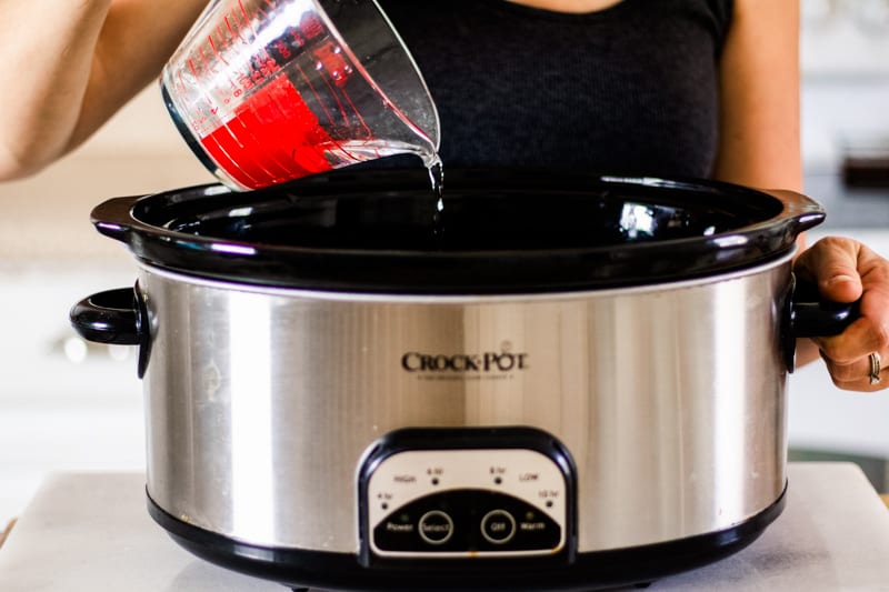 Women pouring water into crockpot.