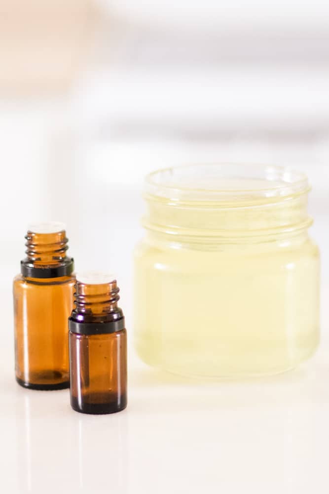 Mason jar of melted wax with essential oil bottles next to it.