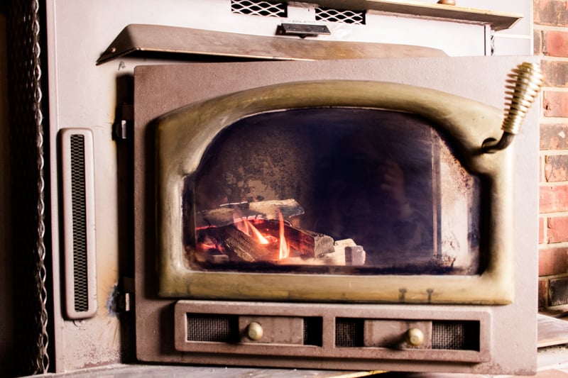 Wood stove door with glass opened with fire inside. 