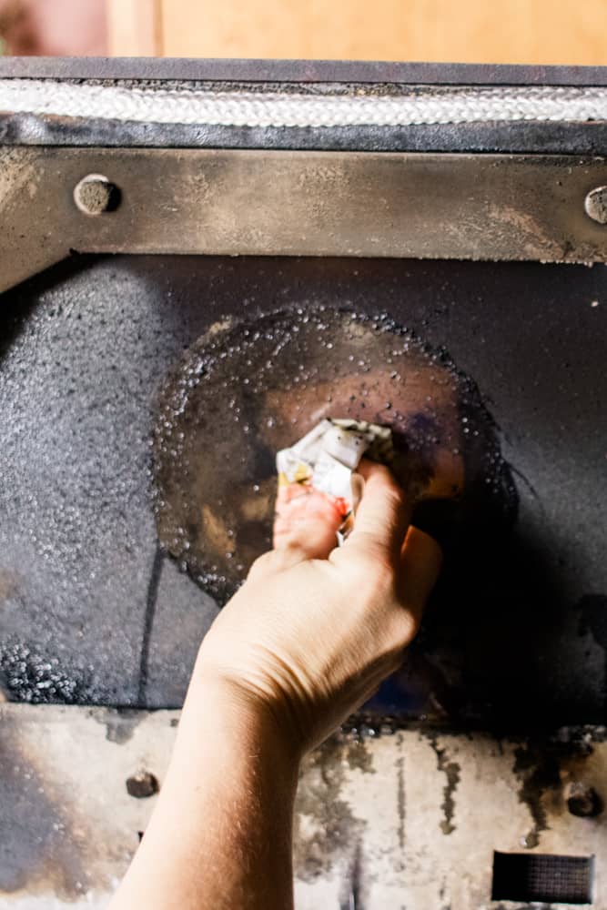 Woman cleaning fireplace glass door with vinegar and newspaper.