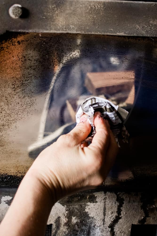 Cleaning fireplace glass door with vinegar and paper.