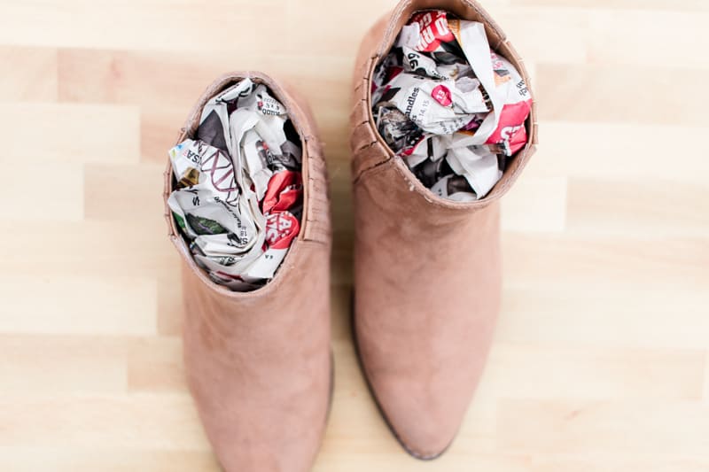 Brown women boots with newspaper stuffed inside them to dry them out.
