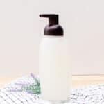 Organic foaming hand soap in a glass soap pump dispenser on countertop.