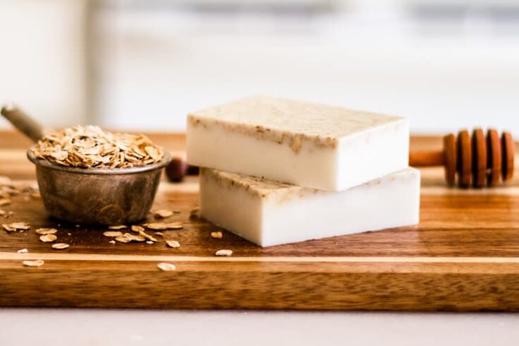 Homemade honey oatmeal soap bars on wooden cutting board.