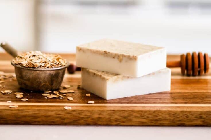 Homemade honey oatmeal soap bars on wooden cutting board.
