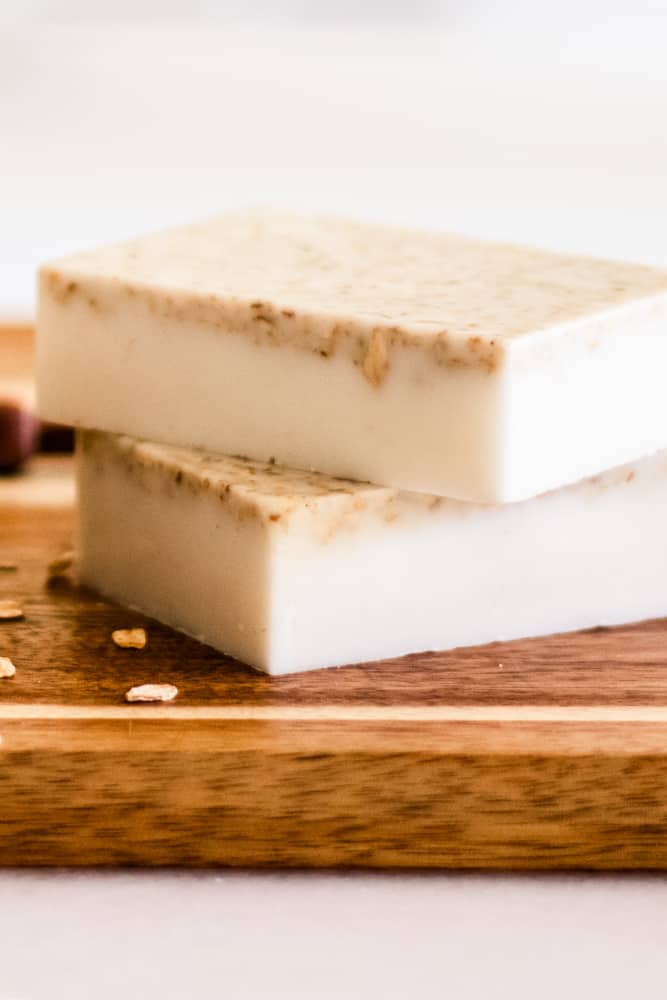 Two oatmeal and honey infused soap bars stacked on wooden table..