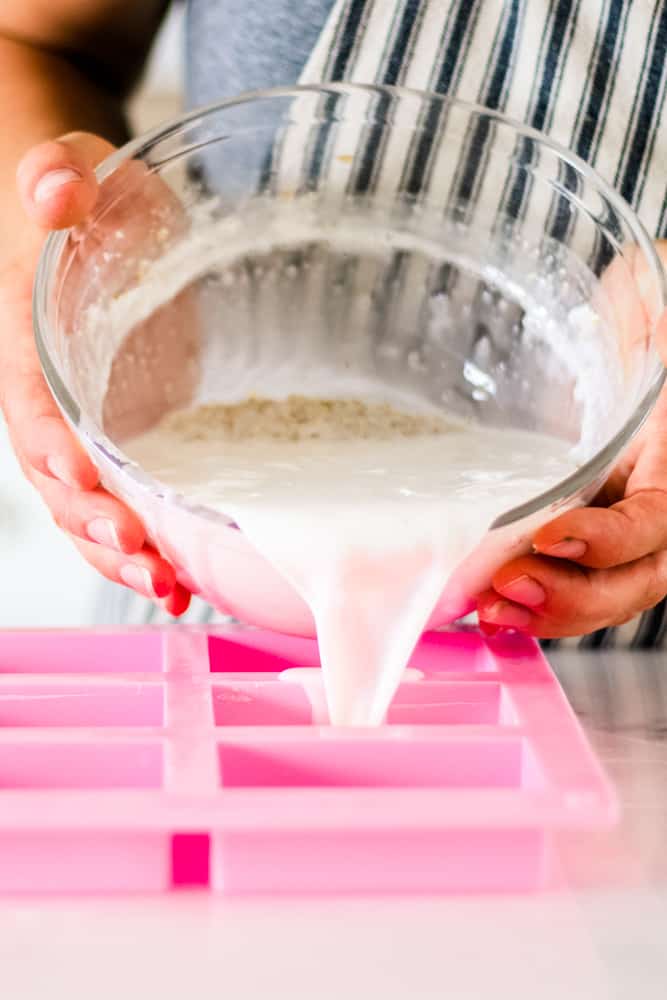 Pouring the soap base from the glass mixing bowl into the silicone molds.