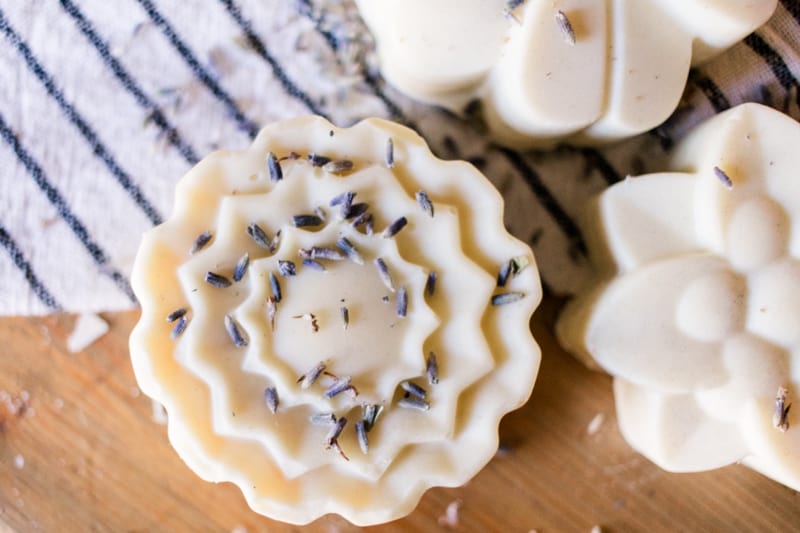 Three bars of lard soap with lavender buds sprinkled on top.