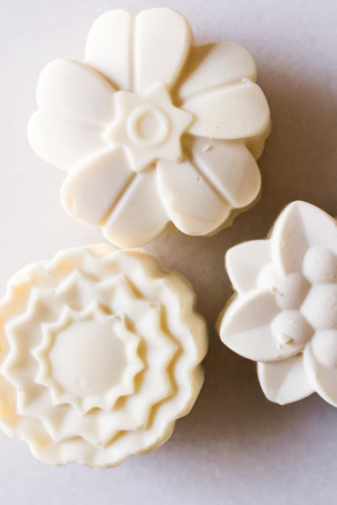 Flower shaped soap bars on white marble table.