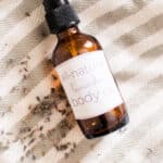 Homemade body oil in a glass dropper bottle with dried lavender sprigs.