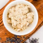 DIY hand mask in a small mixing bowl with lavender on a wooden tray on a white marble countertop.