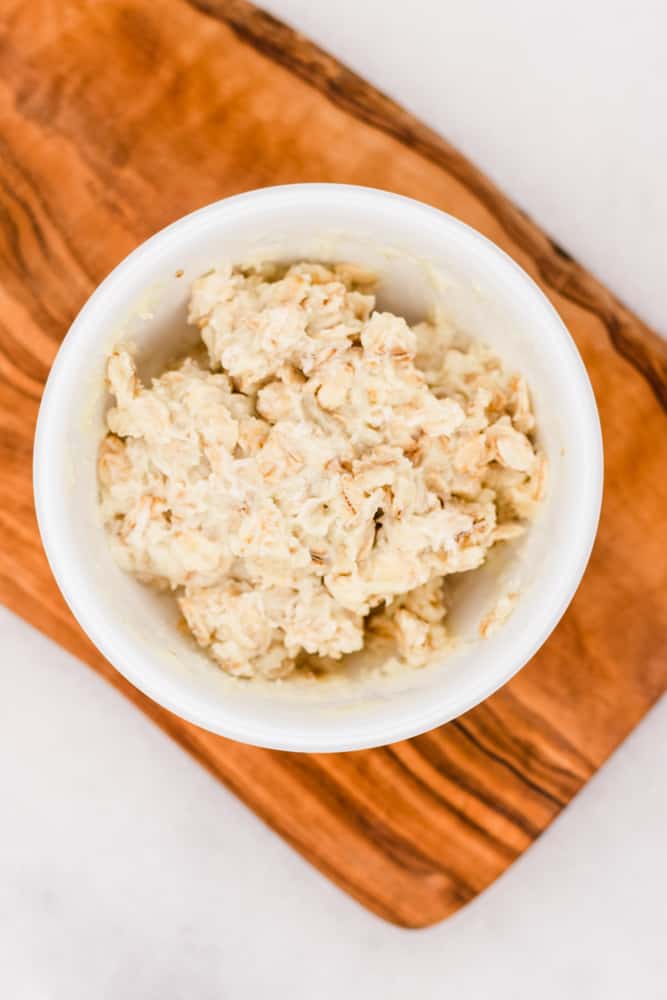 Moisturizing beeswax and oatmeal hand mask on wooden tray.
