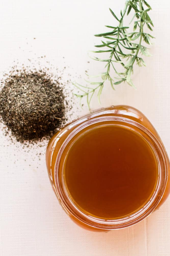 Green tea hair rinse in small mason jar with a small pile of loose leaf green tea next to it.