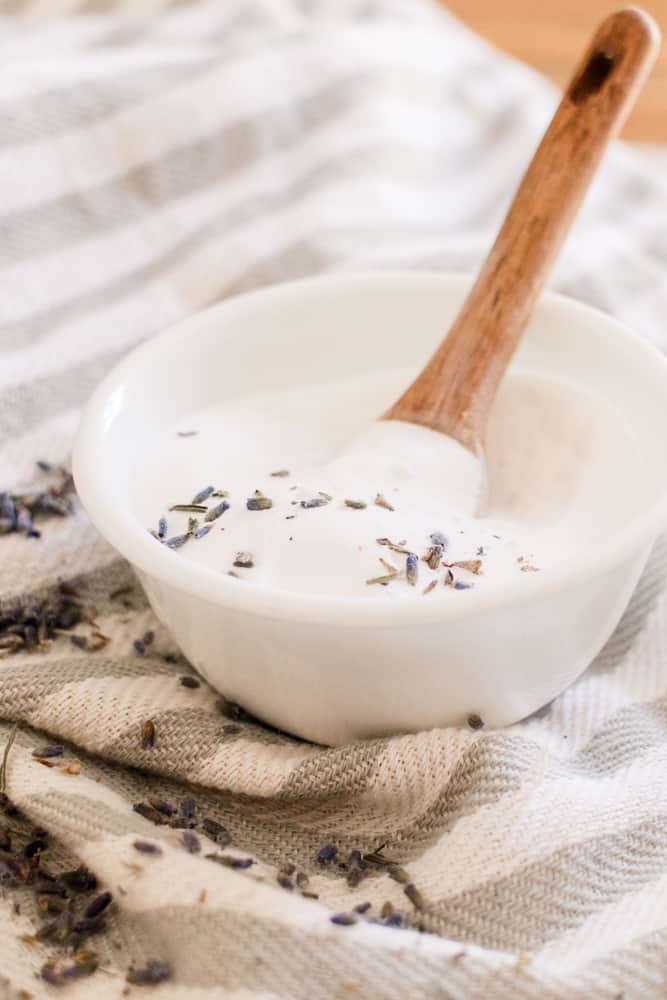 Diy clarifying hair shampoo paste with dried lavender being scooped with a wooden spoon.