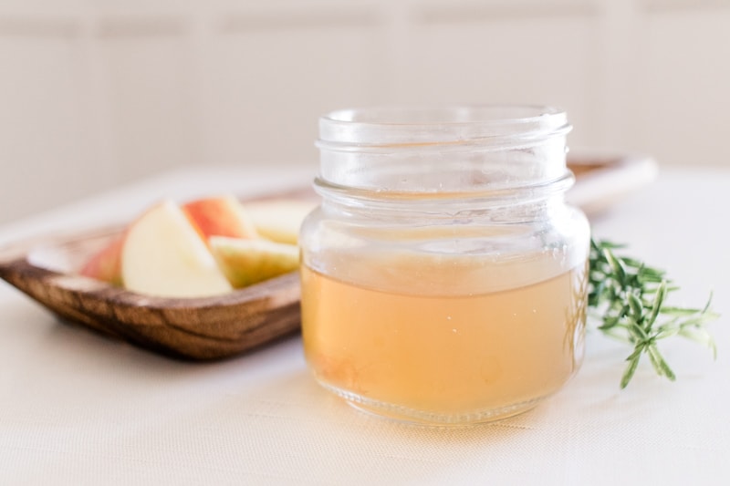 Homemade clarifying shampoo in shallow glass jar on white tablecloth.