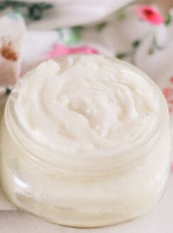Gentle homemade baby lotion on white marble vanity with a decorative flower towel
