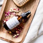 Salt spray for curly hair on wooden tray with sea salt and rose petals.