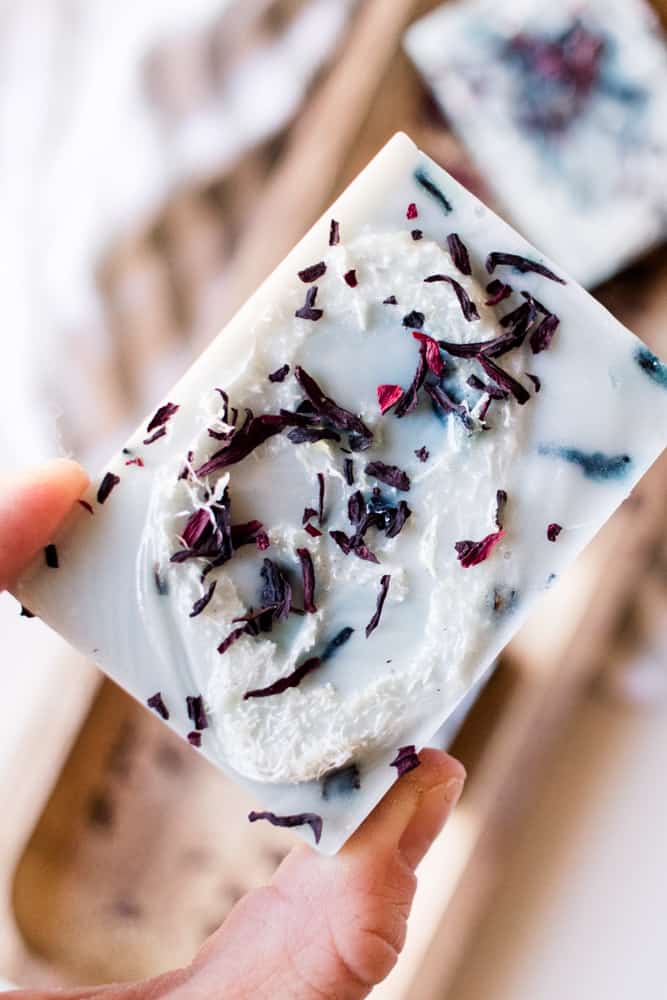 Holding a homemade loofah soap bar with hibiscus flowers infused into it.