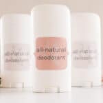 3 DIY natural deodorants with white containers and fragrant flowers.