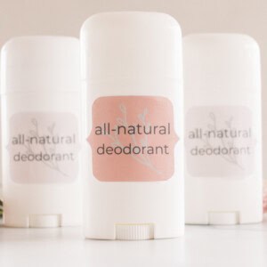 3 DIY natural deodorants with white containers and fragrant flowers.