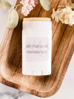Homemade deodorant stick with decorative dried flowers on white marble.