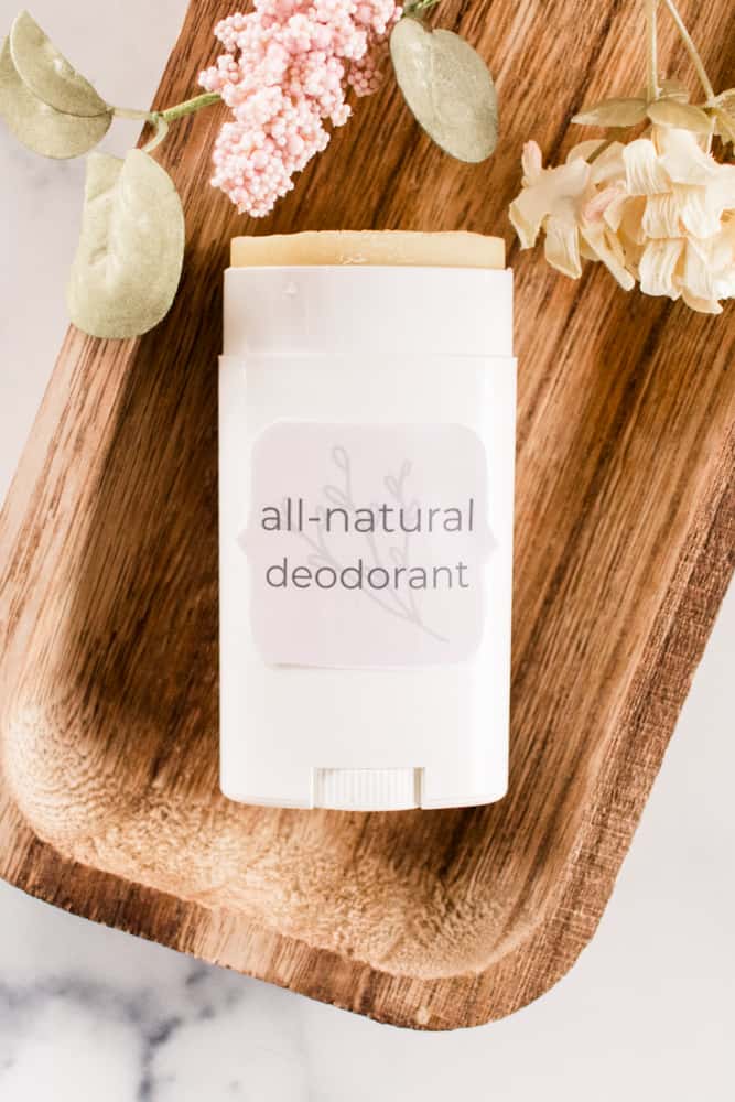 DIY natural deodorant stick with a homemade label on decorative wooden prop.
